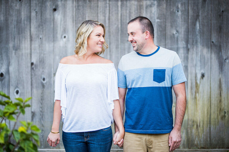 couple looking at each other in front of wood wall Kaitlyn Ferris engaged 
